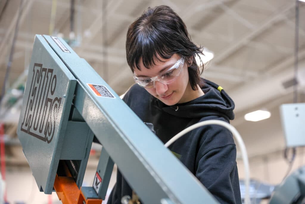 Taryn Reese operating a machine wearing goggles.