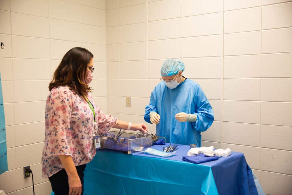 Surgical Technology instructor showing student how to prep the table of surgical instruments.