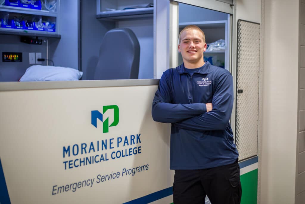 Paramedic student standing in front of ambulance.