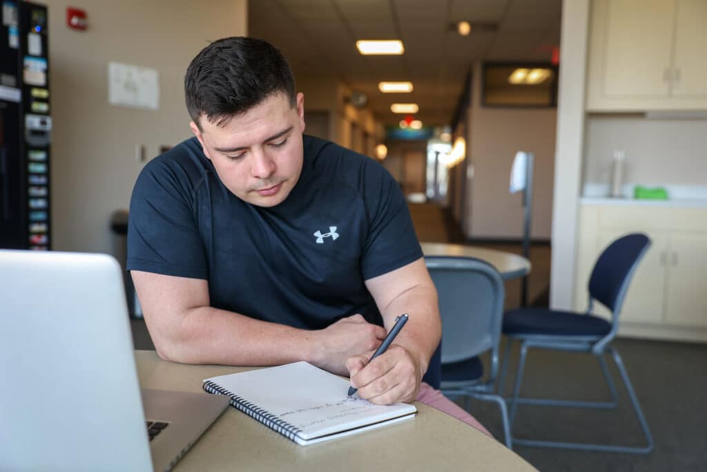 Student writing at a desk in a notebook